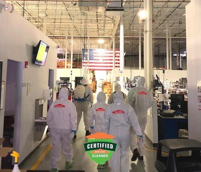 a crew of SERVPRO employees in PPE gear walking inside commercial buildng