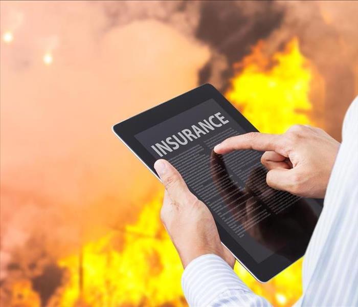 holding tablet with a flames in the background