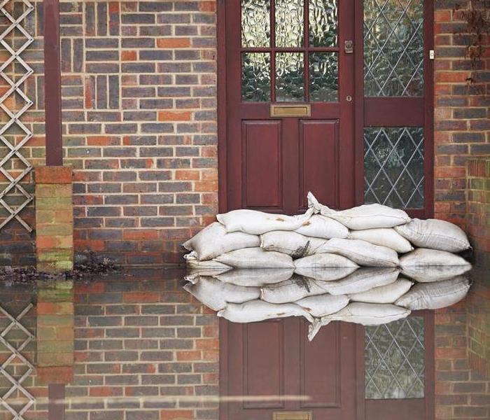 A home with standing water and sand bags at the front door. 