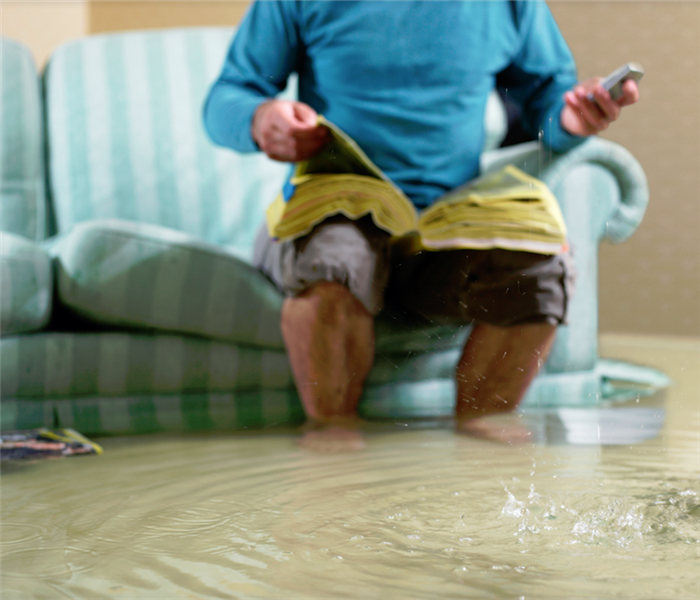 a man sitting in his flooded living room on the phone